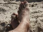 Ett par fötter i den varma sanden.