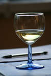 Vinglas Ett glas med vitt vin och en penna.