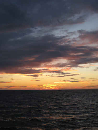 Solnedgång med en segelbåt i horisonten